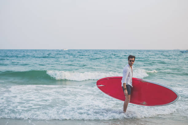 istock Man with red surfboard in water 672724938