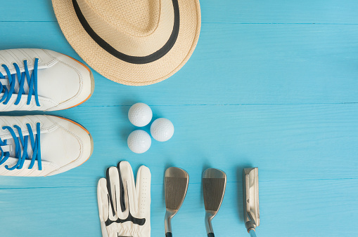 Golf concept : panama hat, glove, golf balls, golf clubs, golf shoes on wooden table. Flat lay with copy space.