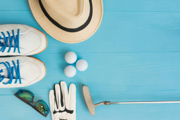 Golf concept : panama hat, glove, golf balls, golf clubs, golf shoes, sunglasses on wooden table. Flat lay with copy space. stock photo