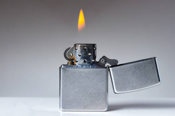 istock Cigarette lighter with flame on white and grey background. Nicotine and tobacco addiction abstract concept. Copy space on the left. 672747186