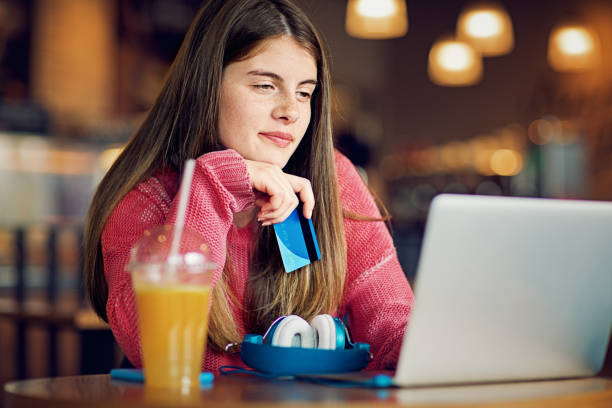 Teenage girl is shopping online in a cafeteria stock photo