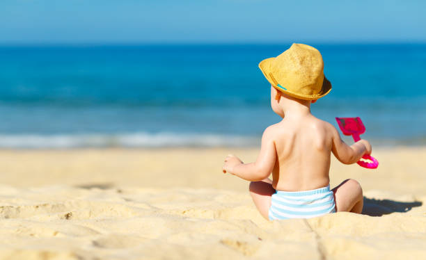 istock baby boy sit back with toys  on beach 672754468