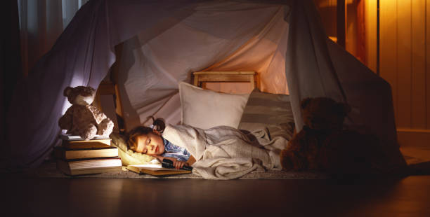 bambina che dorme in tenda con libro e torcia elettrica - dreams child sleeping little girls foto e immagini stock