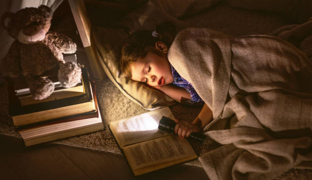 kind mädchen schlafen im zelt mit buch und taschenlampe - tipi bett stock-fotos und bilder