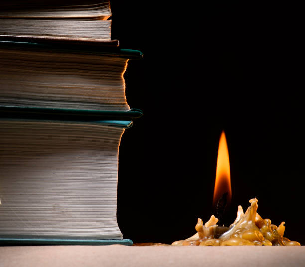 istock stack of books and a burning candle, a dark background. 672772618