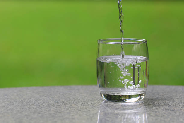 istock Pouring pure water from bottle on table 672775344