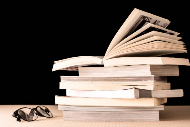 istock Stack of books and eyeglasses on wooden table, Black background 672788726