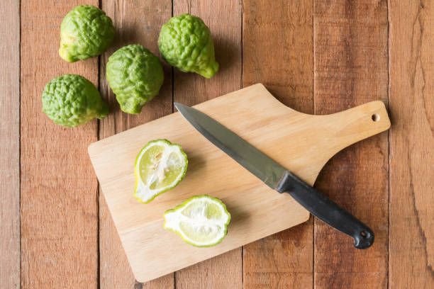 istock Bergamot or kaffir lime with knife on wooden table background. 672788784