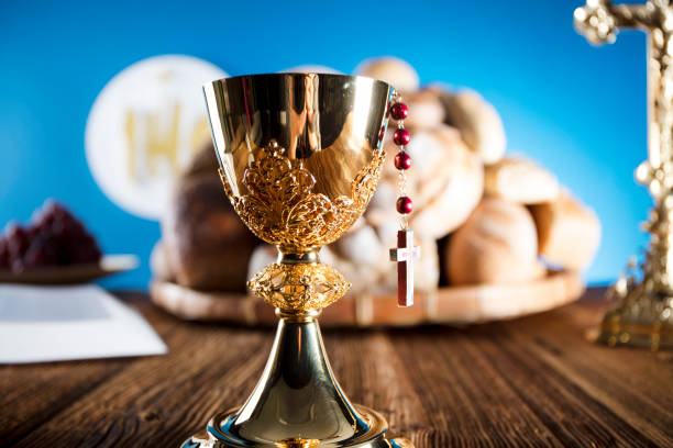 istock First Holy communion. Catholic theme. Crucifix, chalice, bible, bread on rustic wooden table and blue background. 672792154