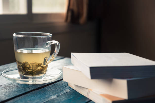 istock Cup of tea with book on wooden table 672792596