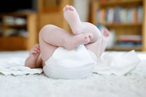 Feet and legs of newborn baby with diaper. Cute little girl or boy two months old Dry and healthy body and skin concept. Baby nursery