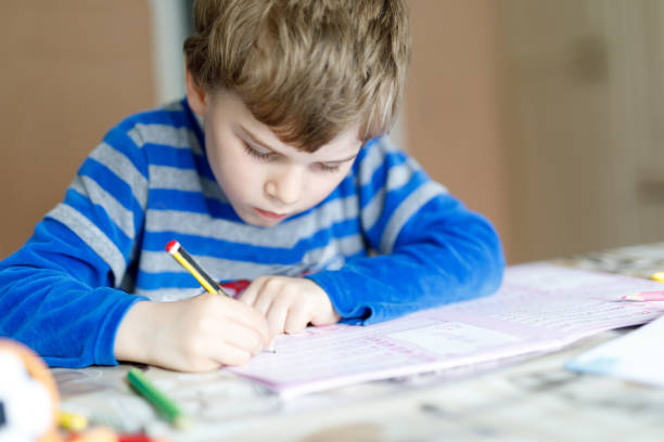 istock Happy school kid boy at home making homework 672806442