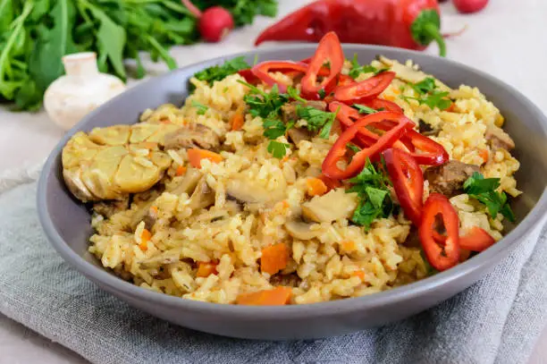 A traditional Asian dish - pilaf with meat, mushrooms and pepper capi in a bowl.