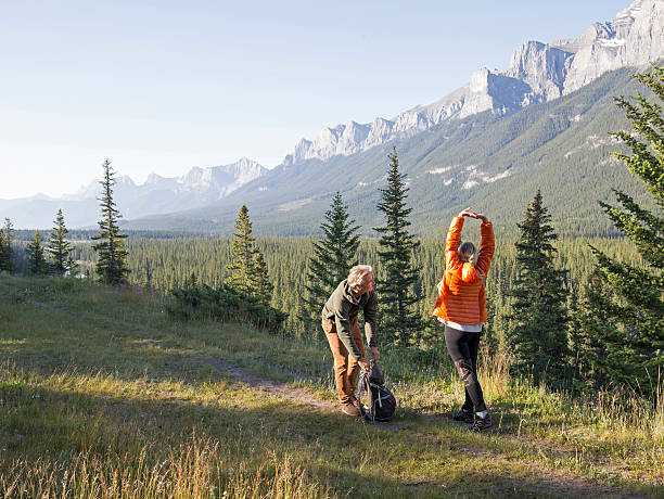 istock Hiking couple stop to stretch by mountain range 672817797