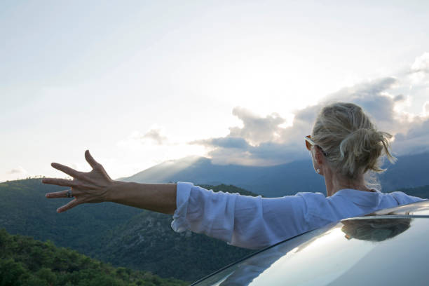 istock Woman admires evening and hillside from car 672817965