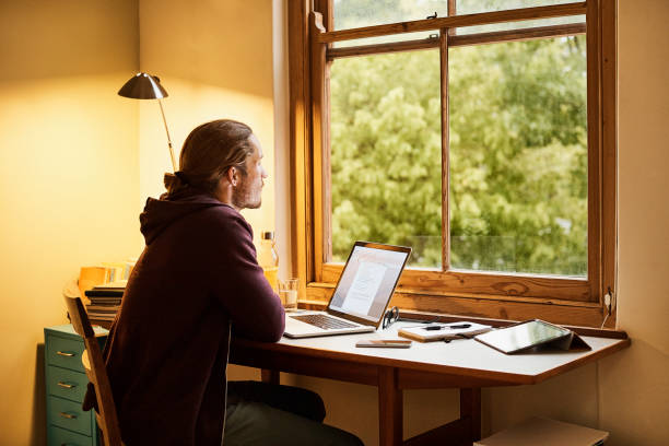istock Man with laptop at desk in home office 672824178