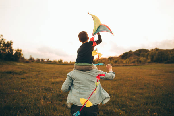 Kite ready for fly off Little boy is running a kite with his father, on a beautiful day they are spending outdoors in nature piggyback photos stock pictures, royalty-free photos & images
