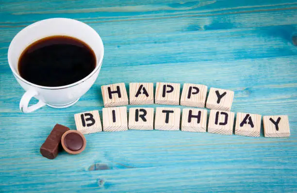 Photo of happy birthday. Coffee mug and wooden letters on wooden background