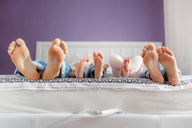 ベッドに横になっている親子の足 - 家族　寝る ストックフォトと画像
