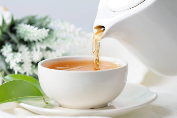 istock pouring hot black tea in a white tea cup 672828080