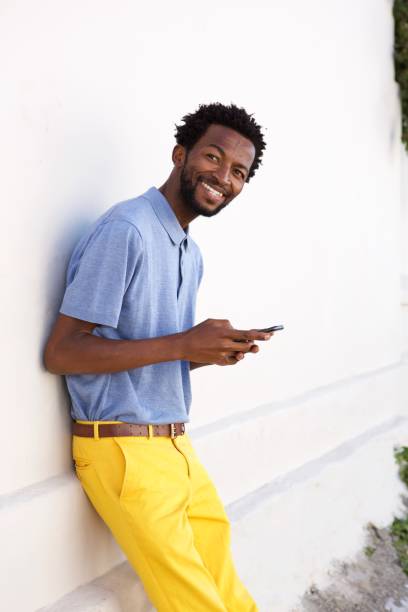 istock handsome man holding smart phone by wall 672846312
