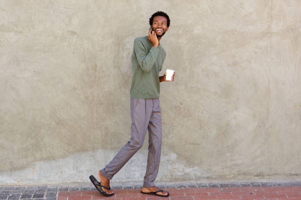 istock Handsome african man walking with smart phone and coffee cup 672846384