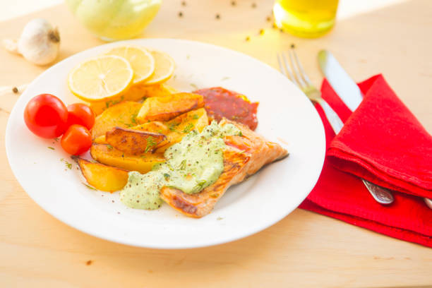 istock Fried salmon and vegetables on plate on wooden table 672852726