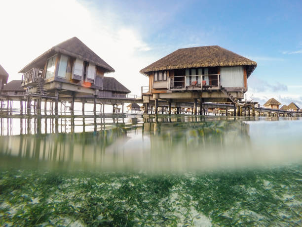 Abstract ocean design with underwater part and water bungalow resort sunset skylight splitted by waterline. Beautiful clouds and bright sun over sea water. Maldives\