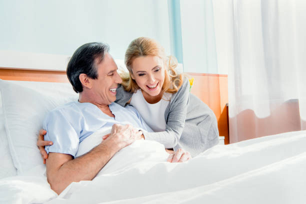 istock happy wife visiting elderly husband in hospital 672866278