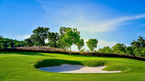 Young woman doing maintenance of a golf course sand trap.