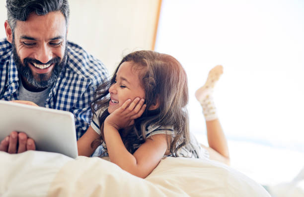 czy możemy obejrzeć ten zabawny znowu tata? - bed child smiling people zdjęcia i obrazy z banku zdjęć