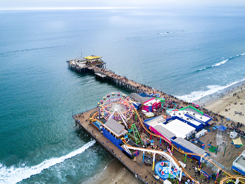 Aerial view of Santa Monica Pier in California, USA with amusement park and crowd.