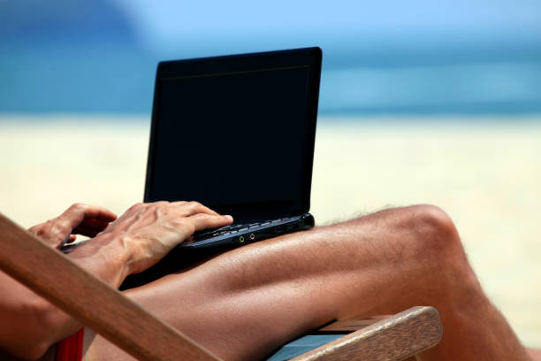 istock The man in an armchair with a computer on a dark blue ocean beach 672892180