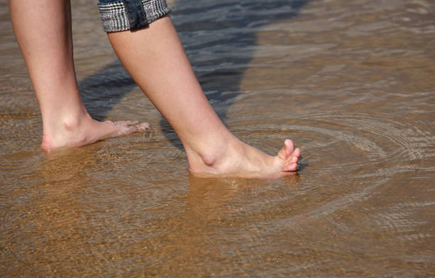 istock Female legs in transparent water 672892340