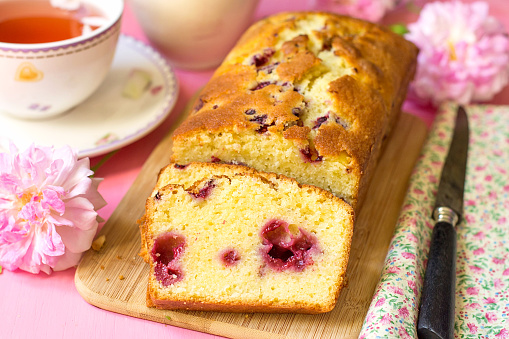 Sweet cake with fruit and berries with tea on pink background