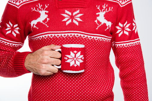 Partial view of man in red knitted sweater holding cup with hot drink