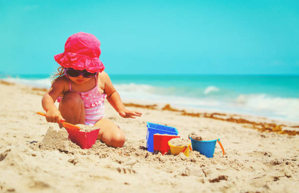 istock cute little girl play with sand on beach 672909760