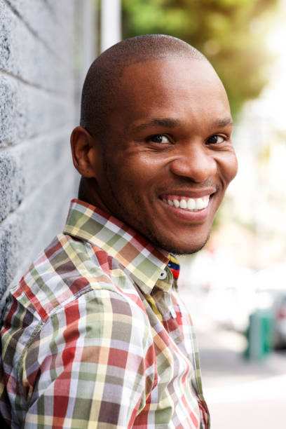 istock happy young black guy leaning to gray wall and smiling 672915002