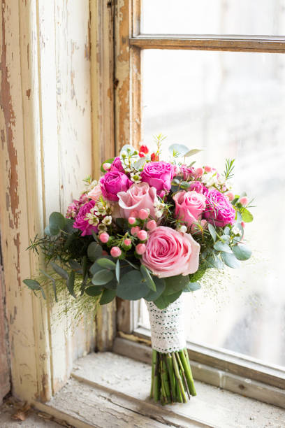 istock Pink wedding roses bouquet placed in a old style window 672915398