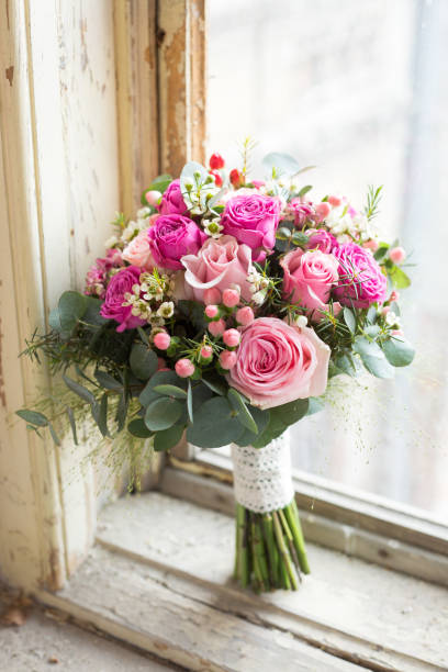 istock Pink wedding roses bouquet placed in a old style window 672915928