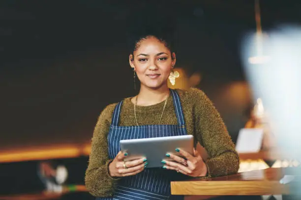 Shot of a young woman using a  digital tablet while working at a coffee shop