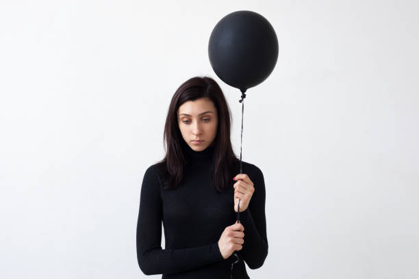 une fille triste tient un ballon noir dans ses mains. - phlegmatic photos et images de collection