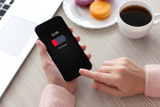 istock Women hands holding phone with low charged battery screen 672935328