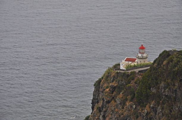 Lonely lighthouse on a cliff on San Miguel Island Azores against the grey ocean