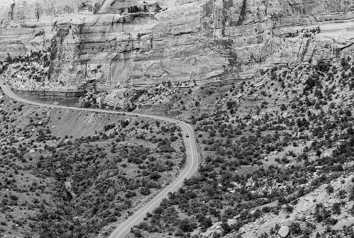 Cars driving the Rim Rock Drive, the road going through the Colorado National Monument, in the Fruita Canyon. The picture is in monochrome.