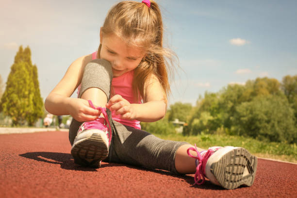 Little girl tying laces on sneakers. stock photo