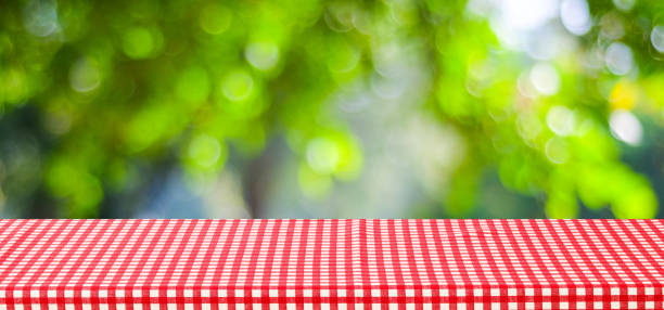 istock Empty table with red tablecloth over blur green tree and bokeh background, for food and product display montage background, banner 672958894