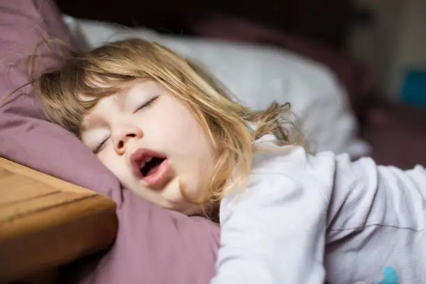 Photo of funny face of child sleeping on king bed