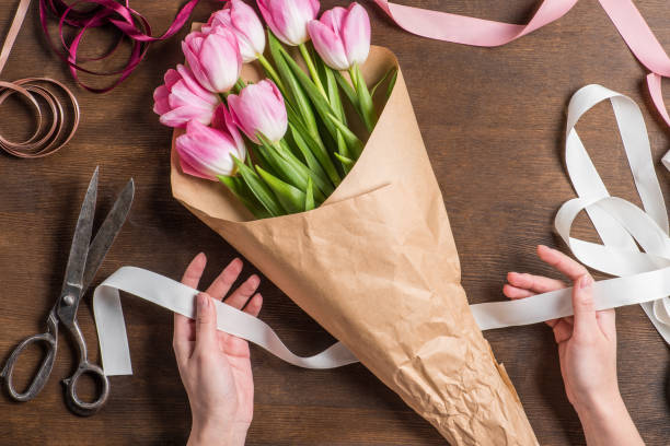 istock pink tulips and hands with ribbon 672973838