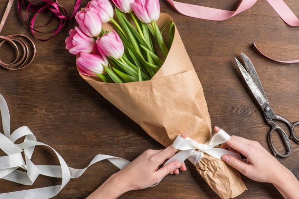 istock pink tulips and hands with ribbon 672975936